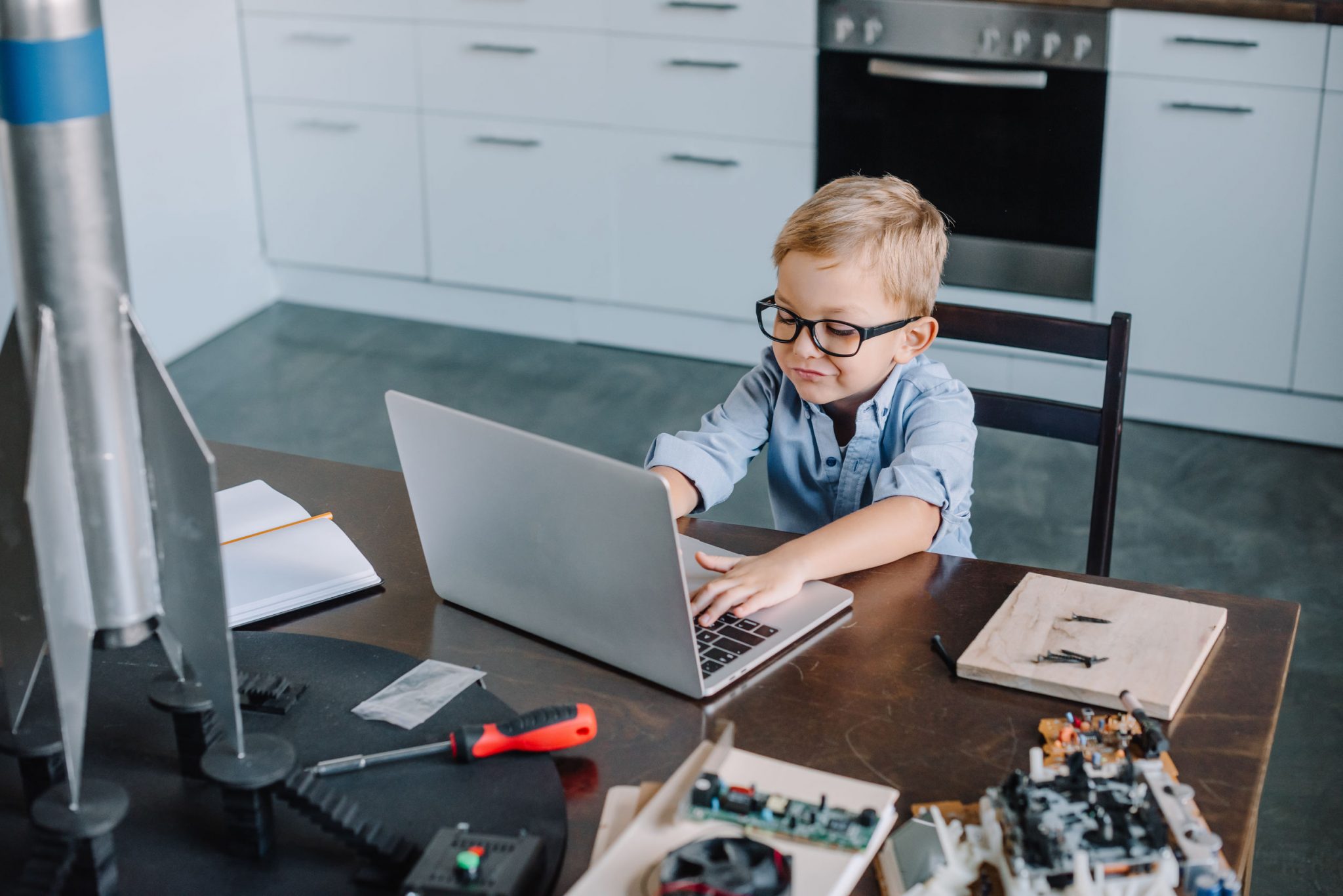 School going boy with his laptop attending online class from home