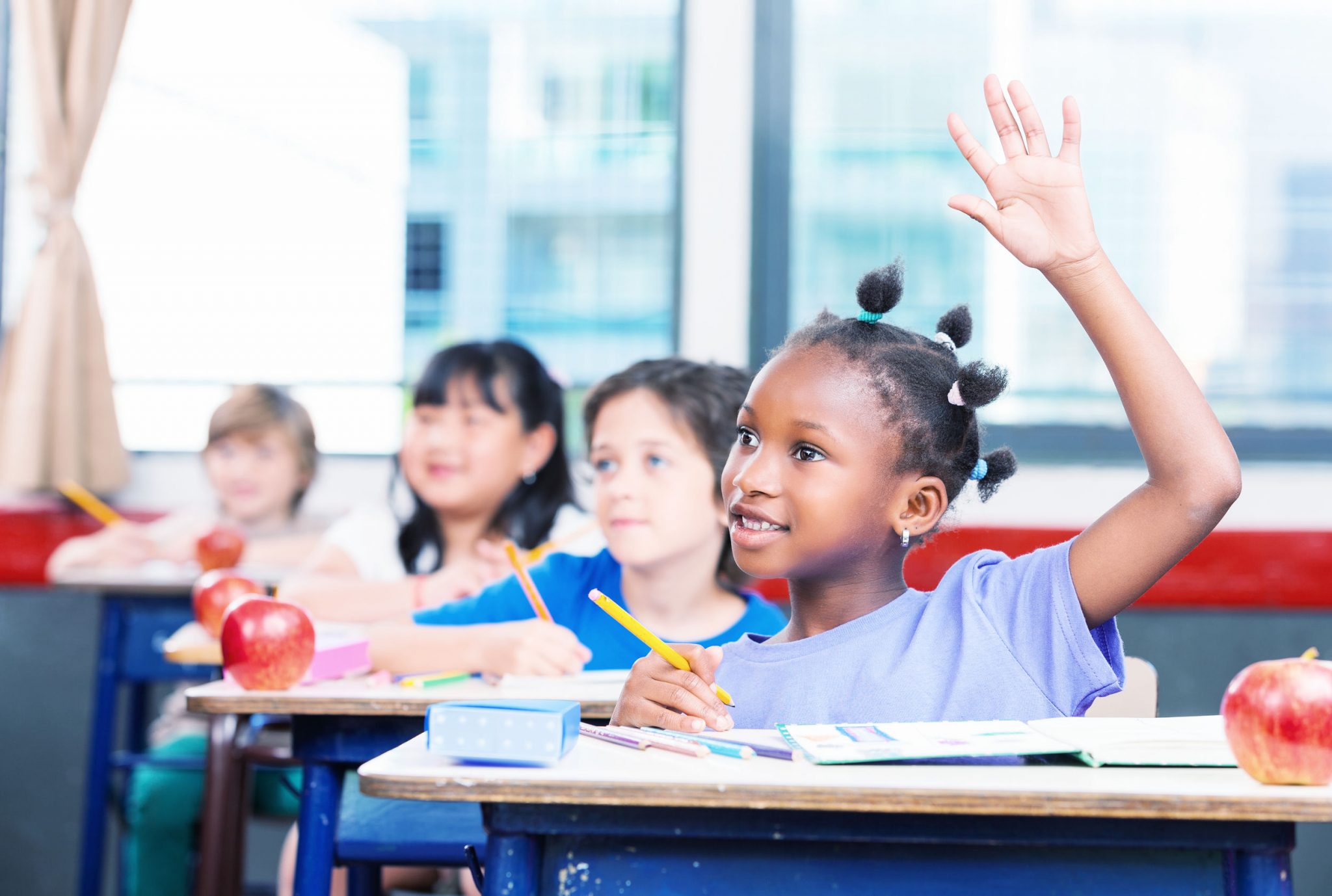 A student raising her hand in a class room