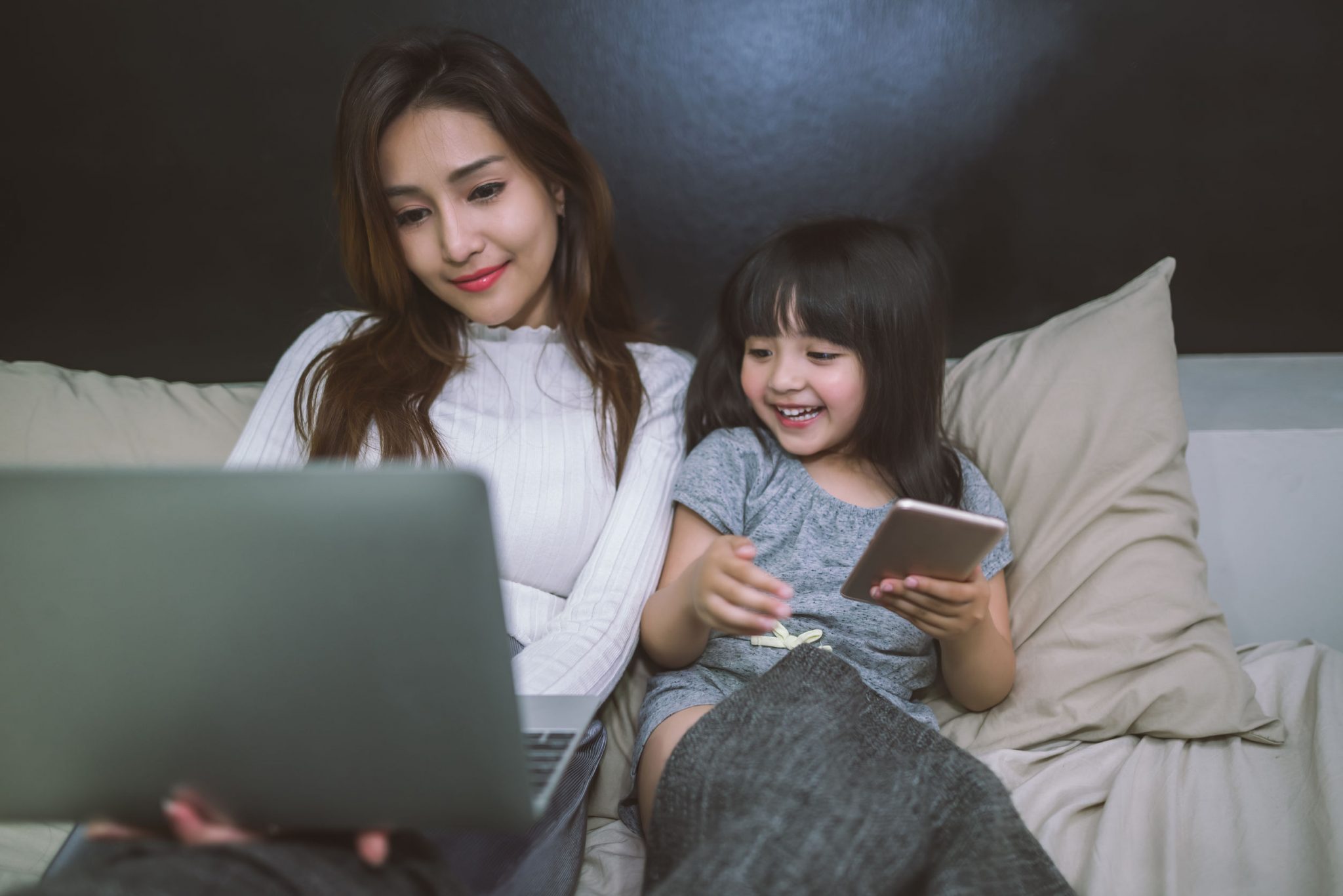 A mother and her female child using phone and laughing together