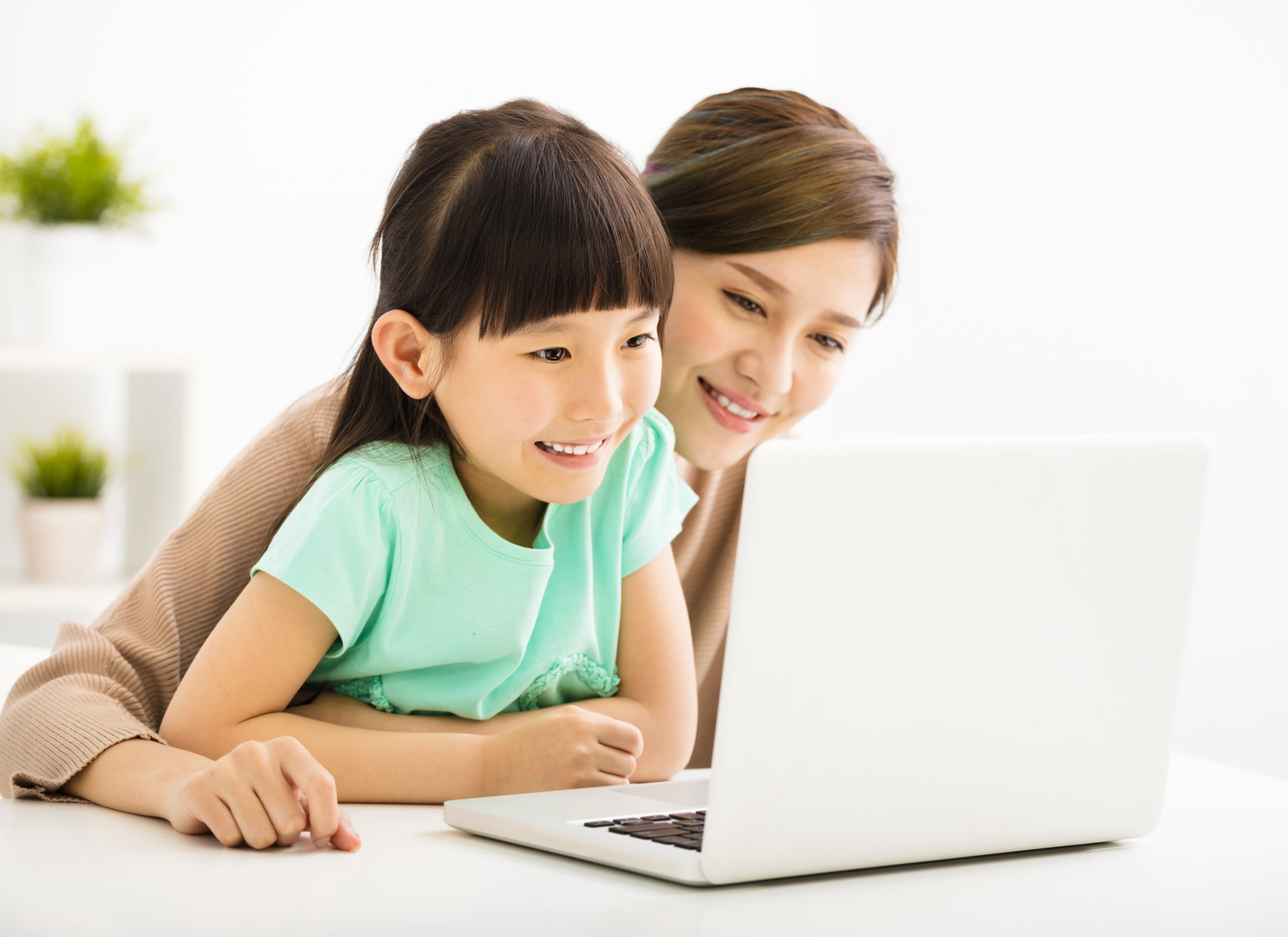 A mother and her child looking at a laptop screen with smiling face