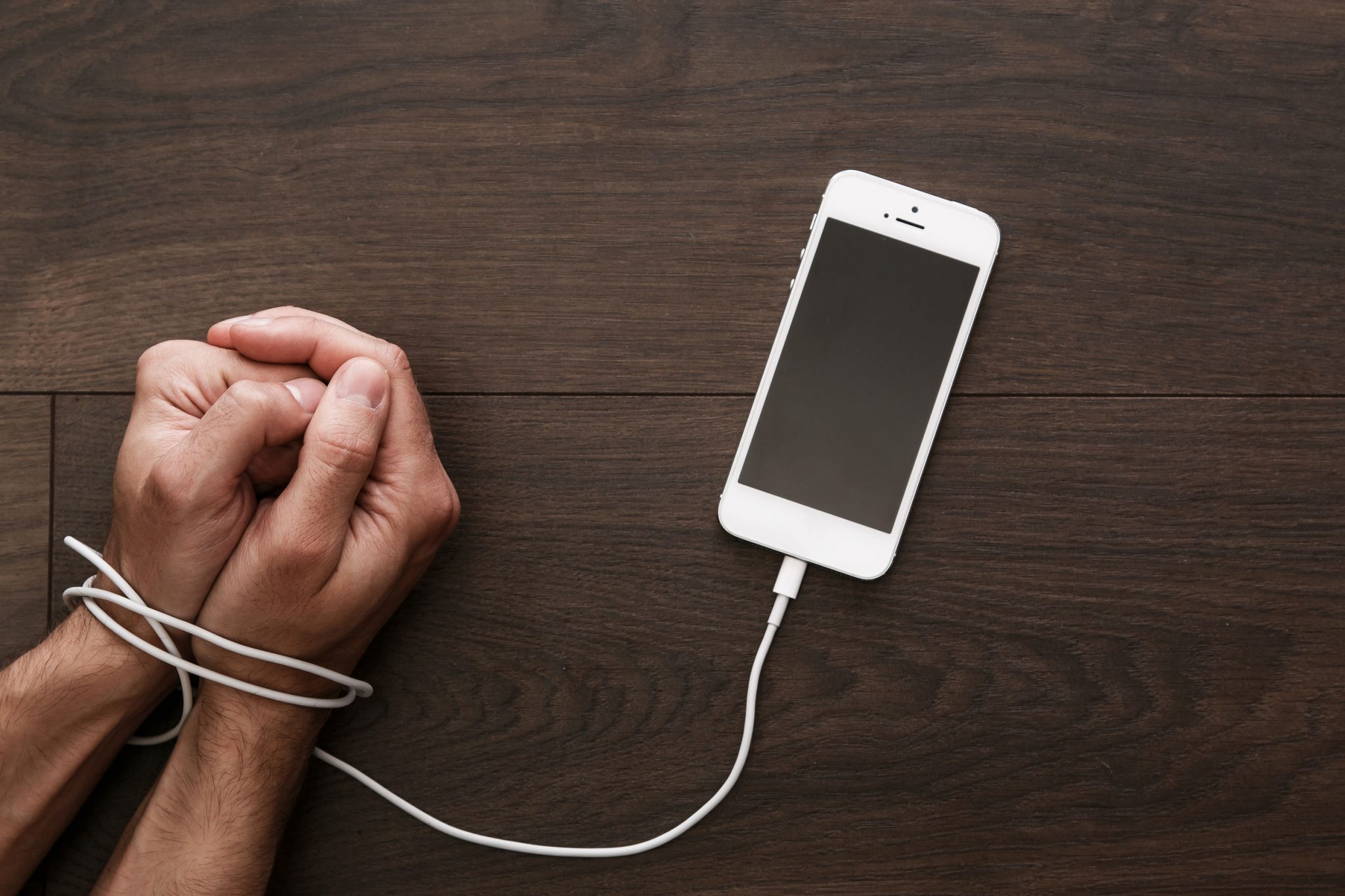 A phone charging cable blocking a man's both hands